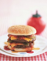 Photo of multipatty hamburger with cheese and pickles on a plate